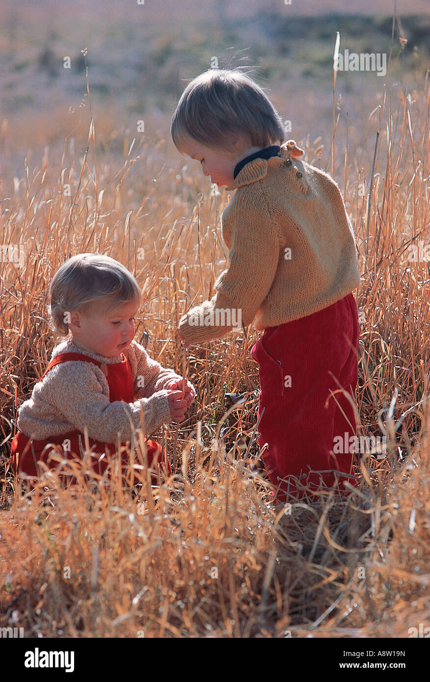 Due bambini che giocano all'aperto in erba secca campo. Foto Stock