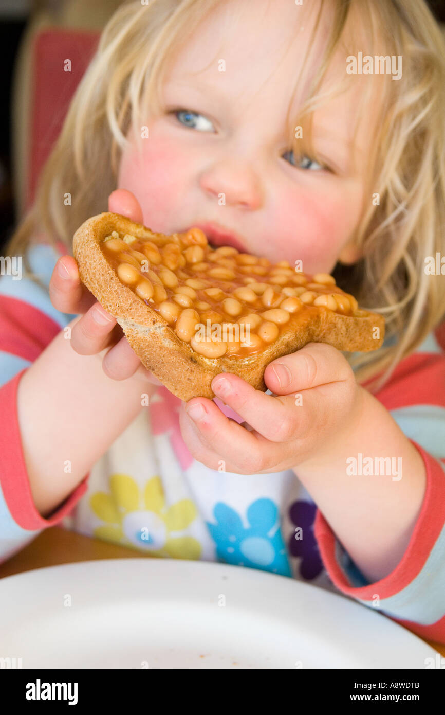 Ragazza giovane mangiare fagioli su pane tostato Foto Stock