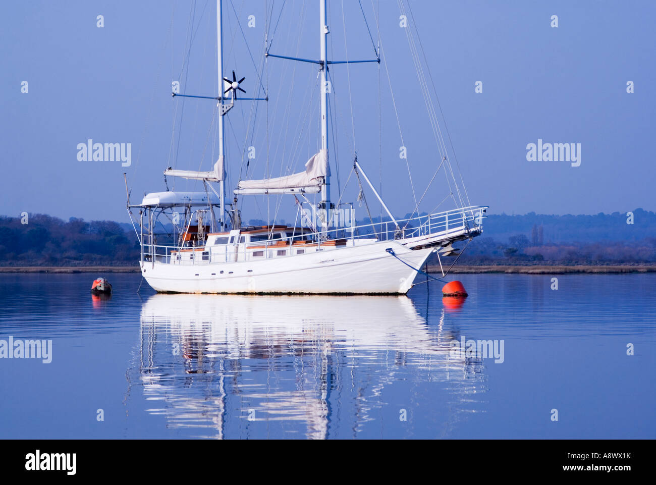 Yacht bianco e gavitelli rossi sulle calme acque blu. Il porto di Poole. Il Dorset. Regno Unito (nome yacht rimosso) Foto Stock