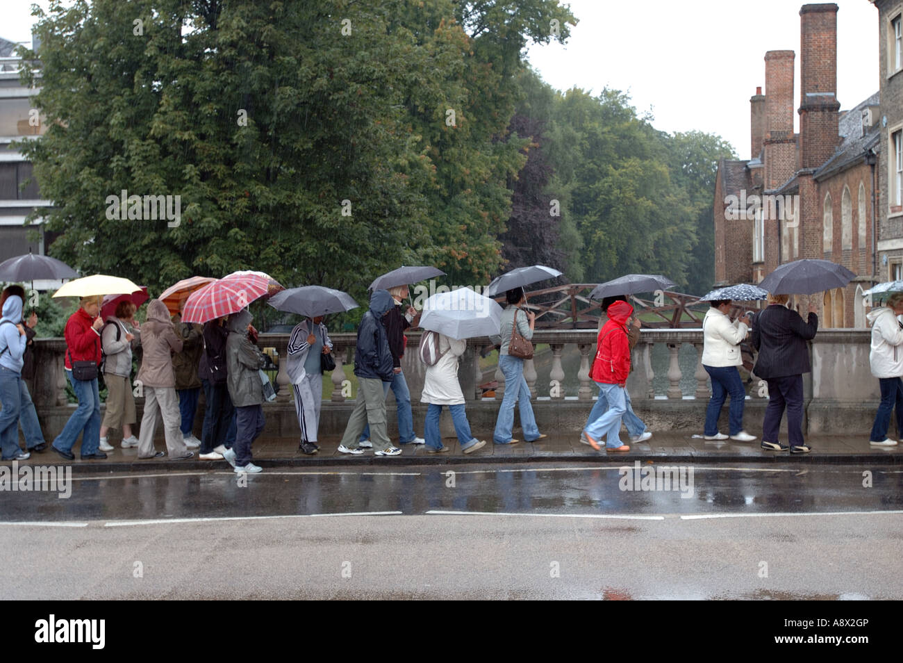 Turisti sotto la pioggia con ombrelloni su Silver Street Cambridge Inghilterra England Foto Stock