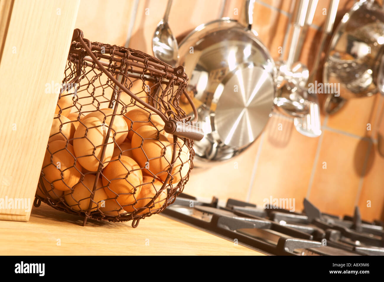 Cesto di uova fresche con utensili da cucina e fornelli a gas in cucina domestica Foto Stock