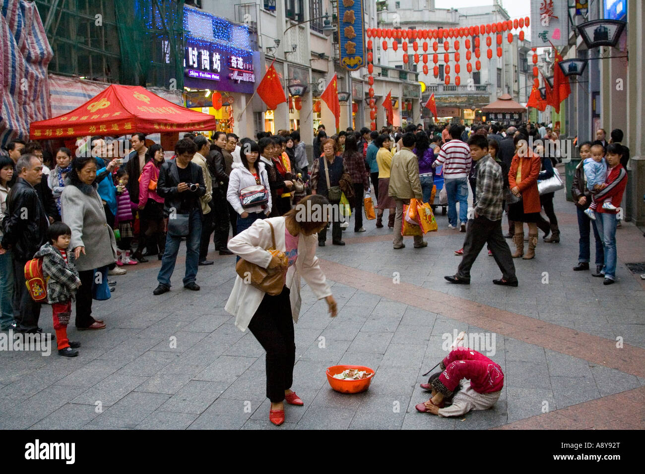 Ragazza cinese Street Performer e mendicante Shang Xia Jiu Square una trafficata strada pedonale per lo shopping mall a Guangzhou in Cina Foto Stock