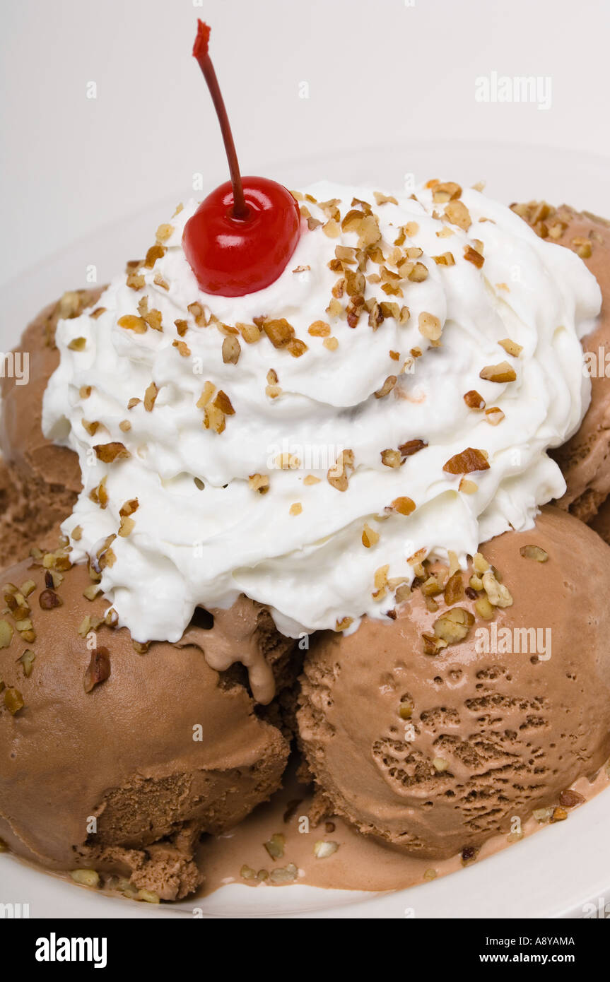 Piatto di gelato al cioccolato con panna montata la ciliegia e dadi Foto Stock