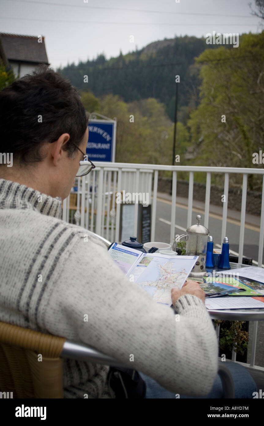 Uomo di lettura guida turistica a outdoor cafe Betws y COED SNOWDONIA national park gwynedd Galles del nord Foto Stock