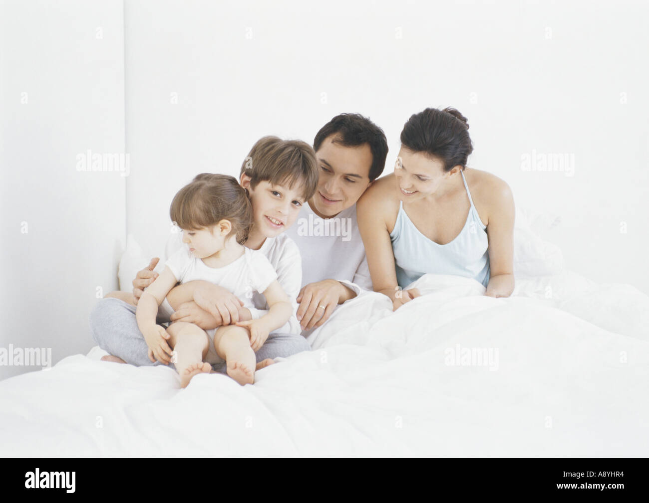 Famiglia seduta a letto insieme Foto Stock