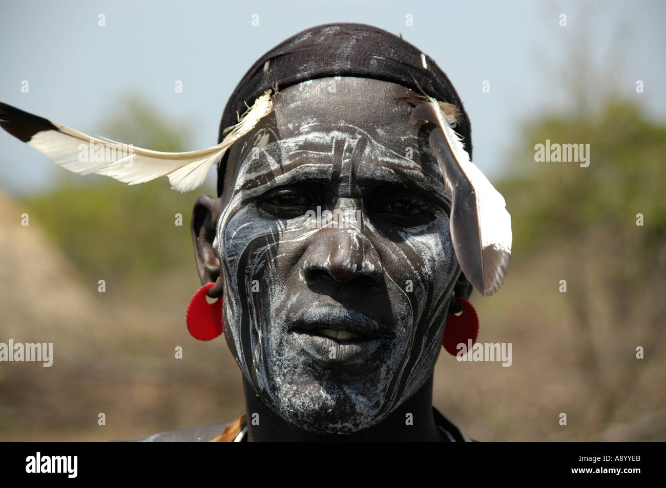 Dipinto di bianco volto di un uomo con le piume al suo capo del popolo Mursi vicino a Jinka Etiopia Foto Stock