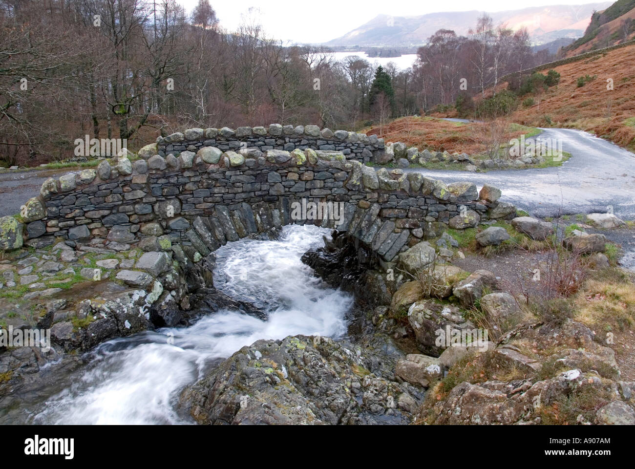 Vista invernale storico ponte di pietra di Ashness nuovo muro di balaustra ruscello che scorre velocemente paesaggio del Distretto dei Laghi di Borrowdale a Skiddaw Inghilterra Regno Unito Foto Stock