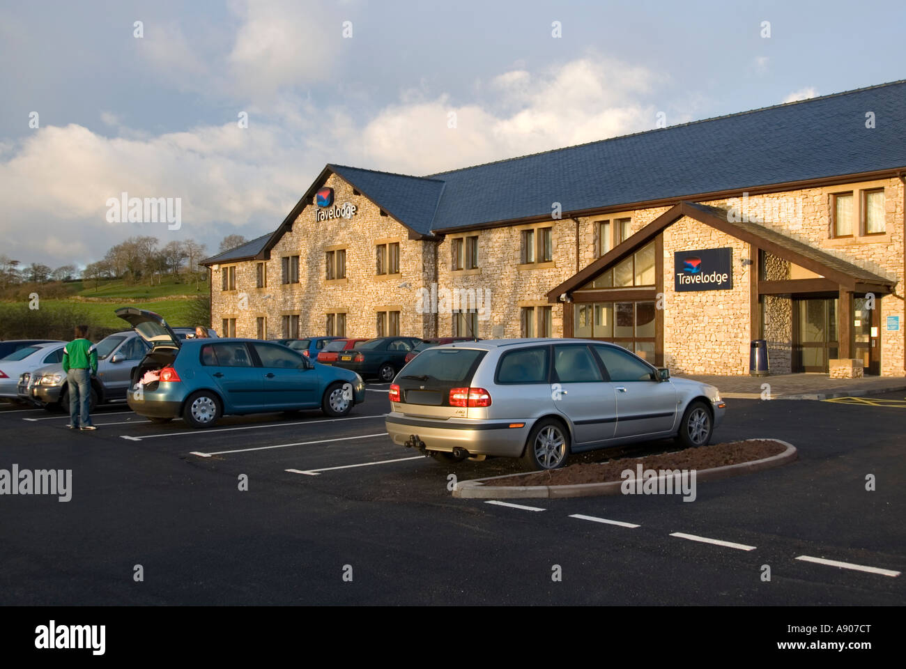 Lake District Travelodge hotel facciata anteriore & reception parcheggio auto in baie e gli ospiti in partenza in auto inizio inverno mattina Kendal Cumbria Inghilterra REGNO UNITO Foto Stock