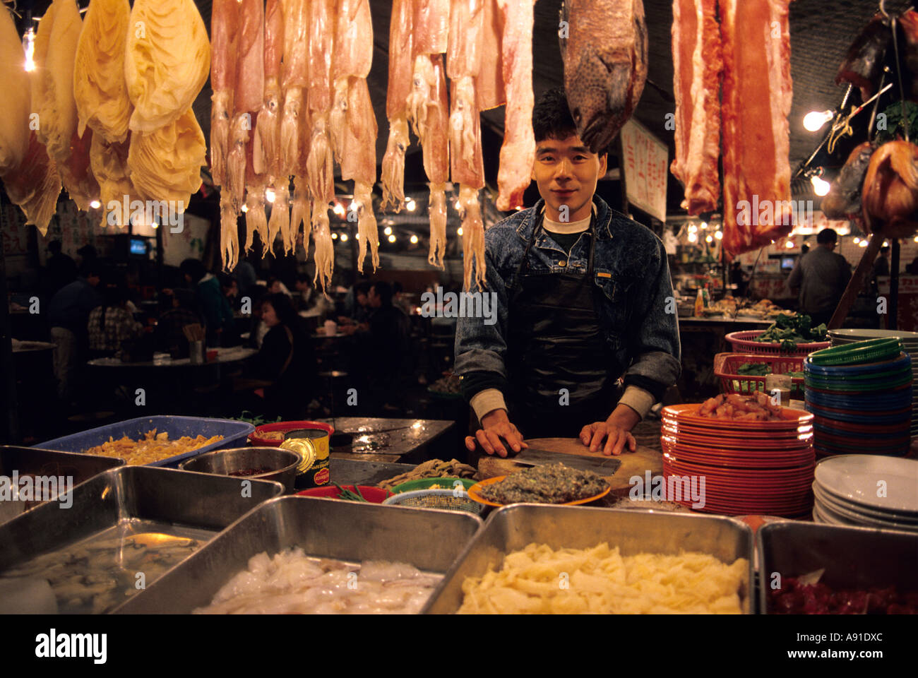 Un uomo lavora ad una notte di mercato vendono la carne e il pesce in Hong Kong. Foto Stock