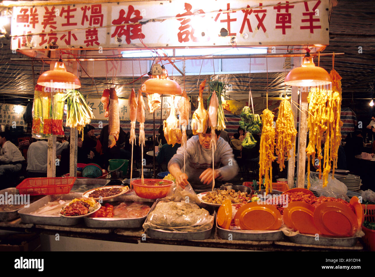Un uomo lavora ad una notte di mercato vendono la carne e il pesce in Hong Kong. Foto Stock