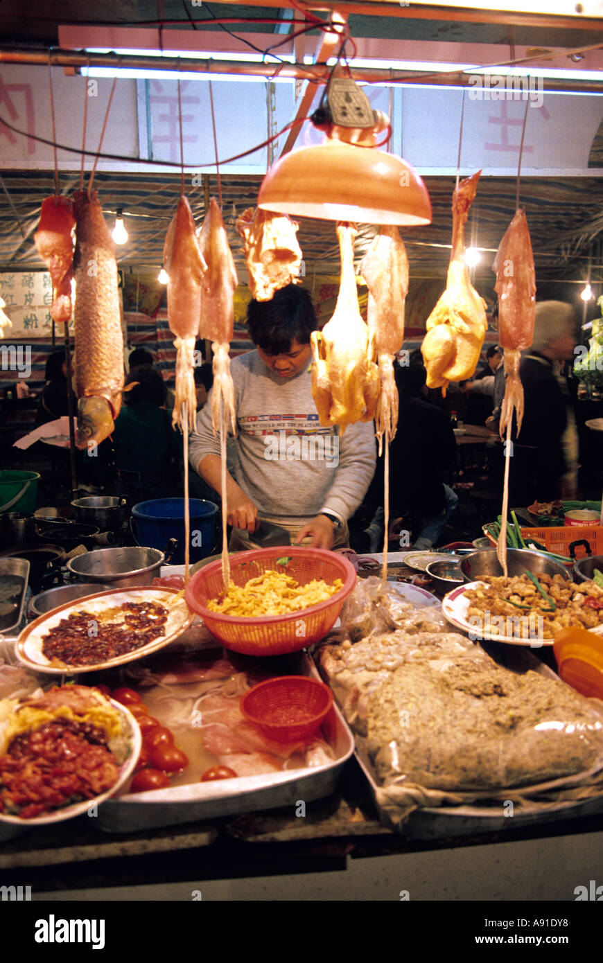 Un uomo lavora ad una notte di mercato vendono la carne e il pesce in Hong Kong. Foto Stock