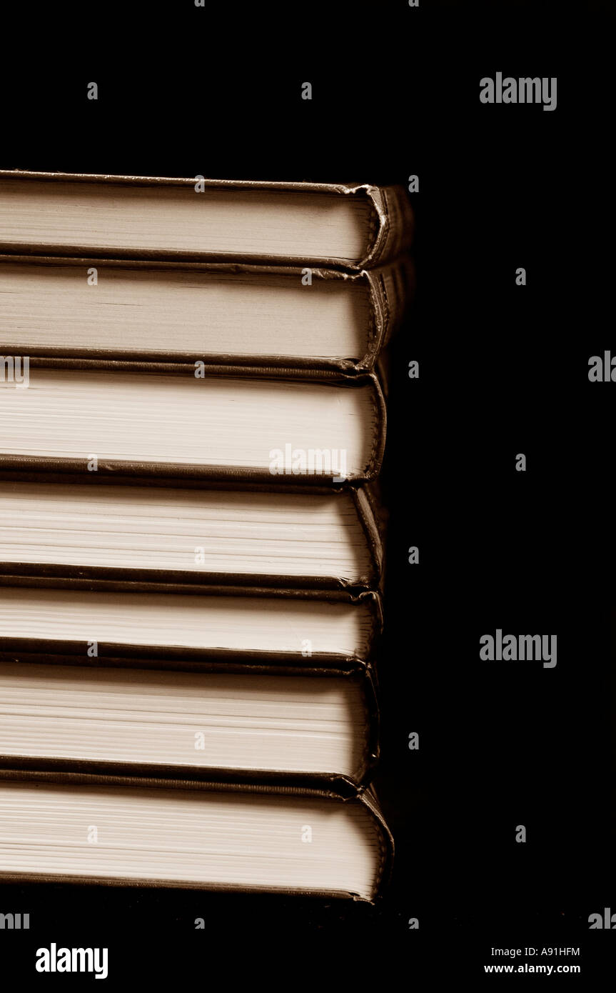 Pila di libri con copertina rigida su sfondo nero Foto Stock