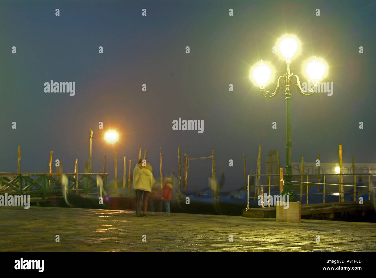 Persone al servizio gondole di notte Personen bei den angebundenen Gondeln im Hafen am Markusplatz bei Nacht in Venedig Foto Stock