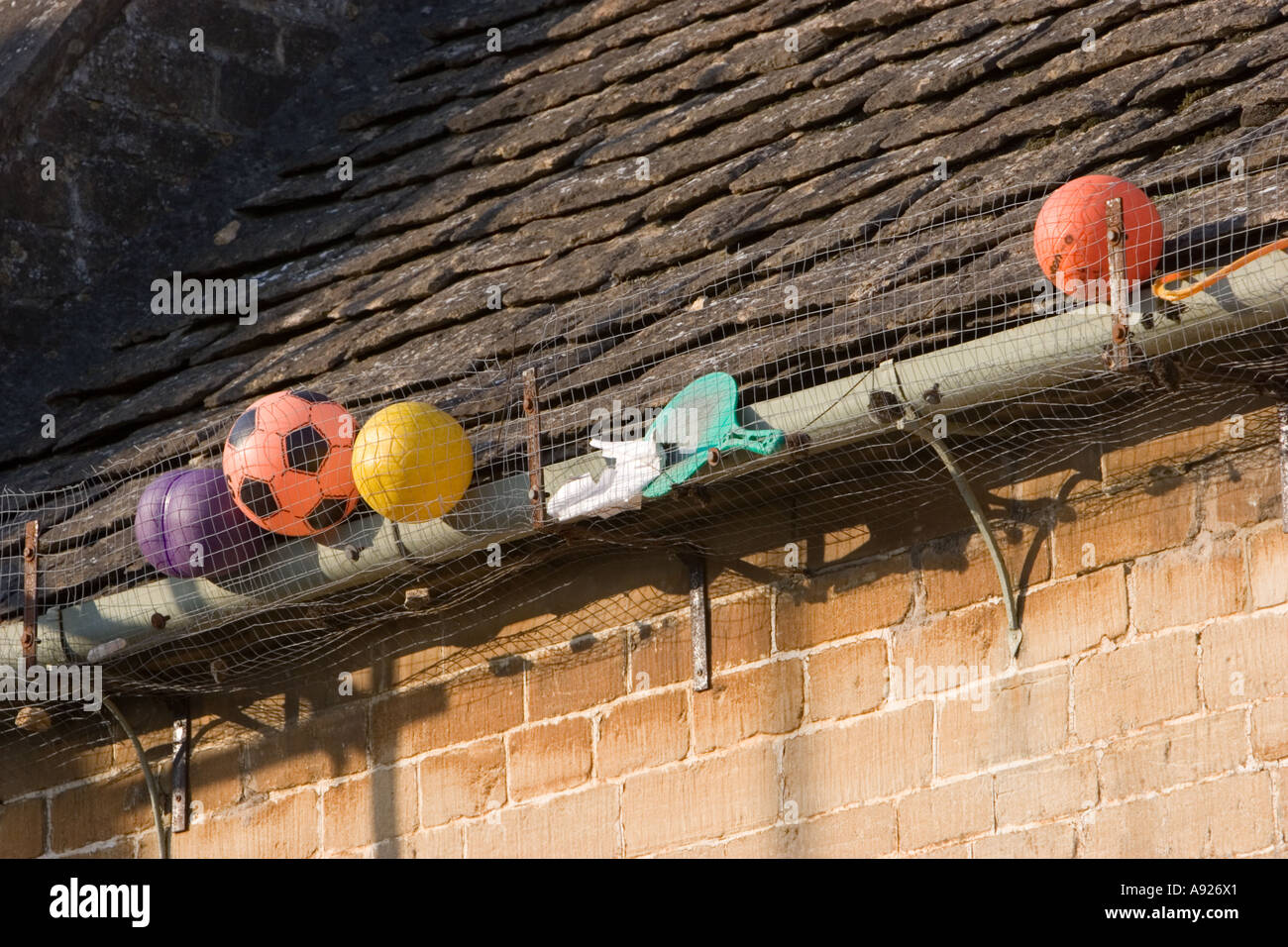 Parco giochi giocattoli quali palle e palloni persi in grondaie sul tetto della scuola Foto Stock
