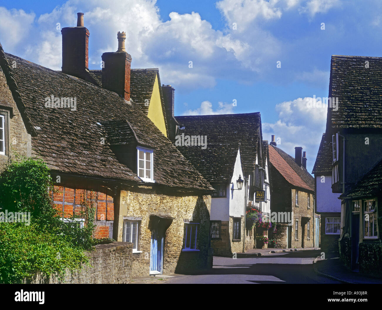 Lacock Village con il segno della pensione Angel e ristorante, vista lungo Church Street con storici cottage LACOCK Wiltshire Inghilterra UK Foto Stock