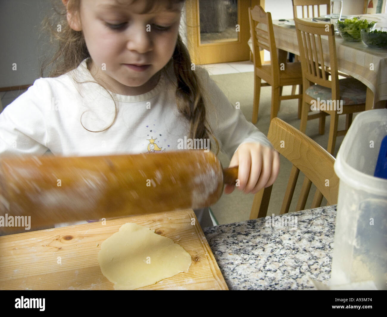 Giovane ragazza 5 cinque anni è la laminazione della pasta con un mattarello preparando per famiglia pasto Foto Stock
