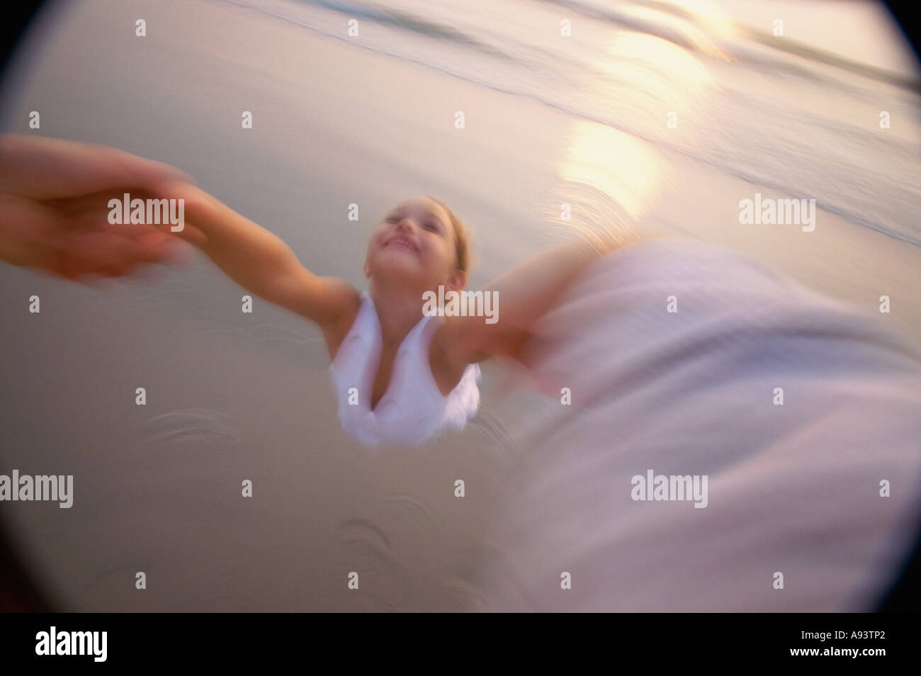 Angolo di alta vista delle mani di una persona swinging una ragazza sulla spiaggia Foto Stock