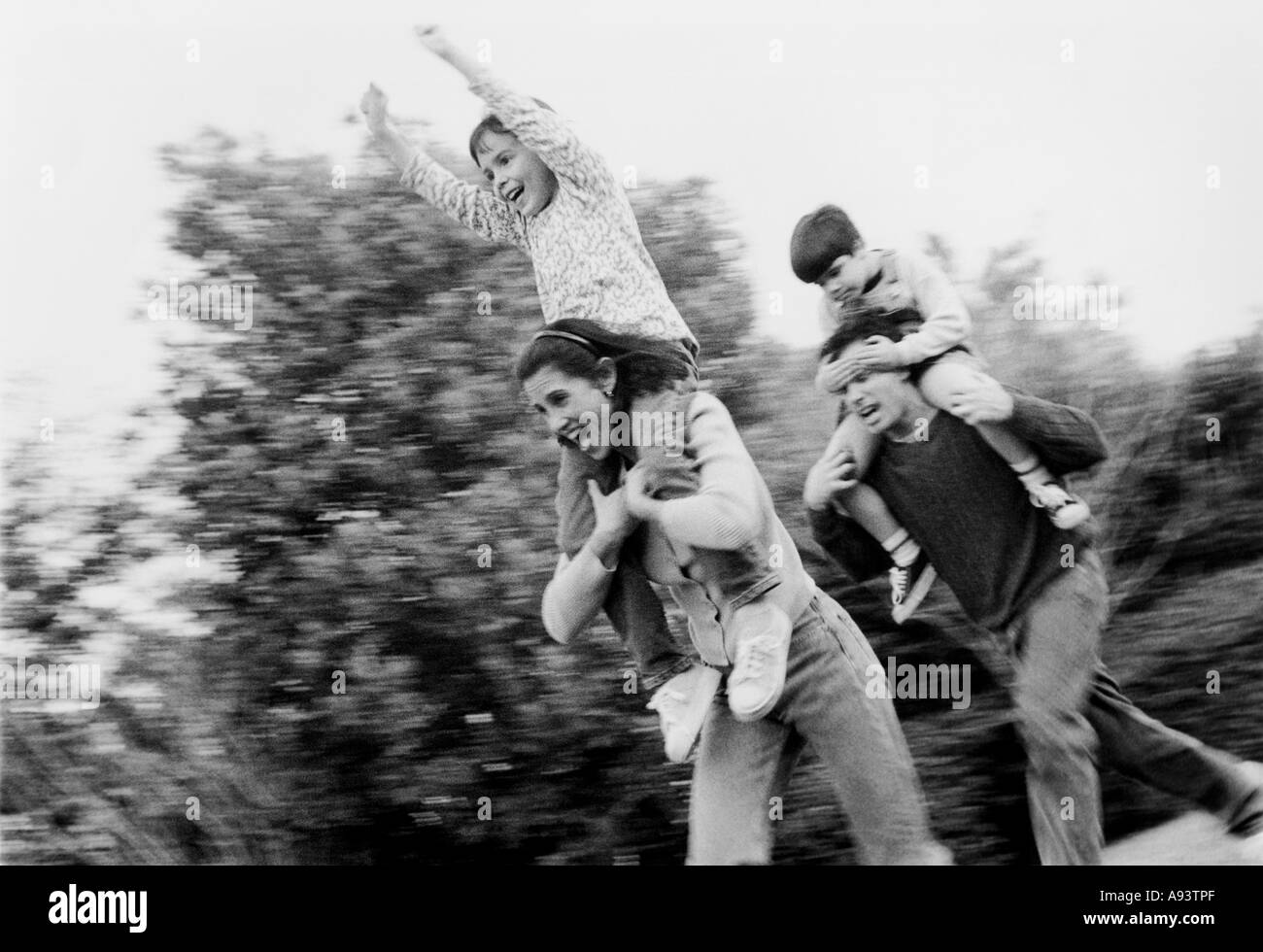 Basso angolo di visione dei genitori che trasportano i loro figli sulle loro spalle Foto Stock