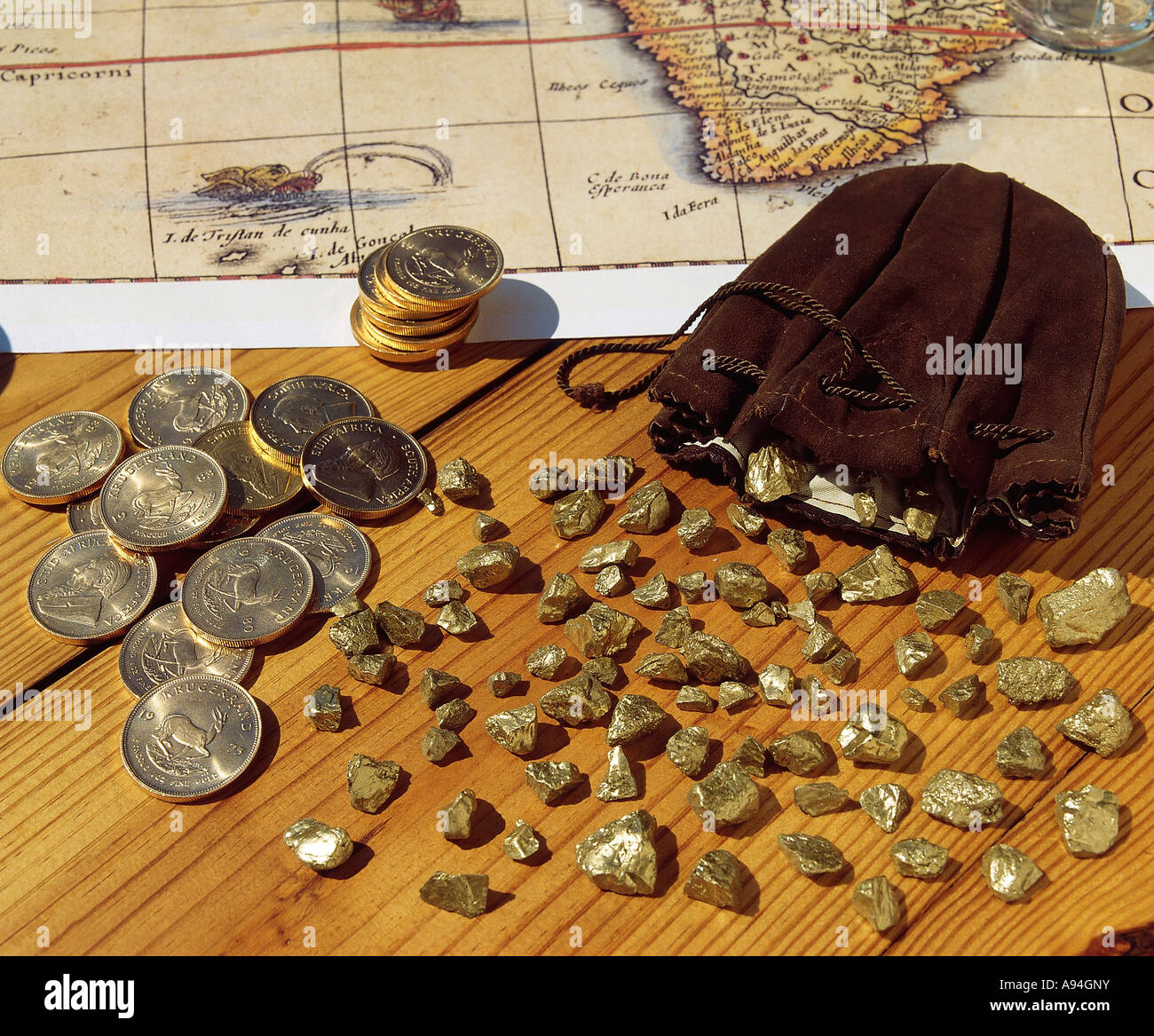 Kruger Rand monete d oro e oro Lingotti sparsi su un tavolo di legno con una vecchia cartina del Sud Africa in background Foto Stock