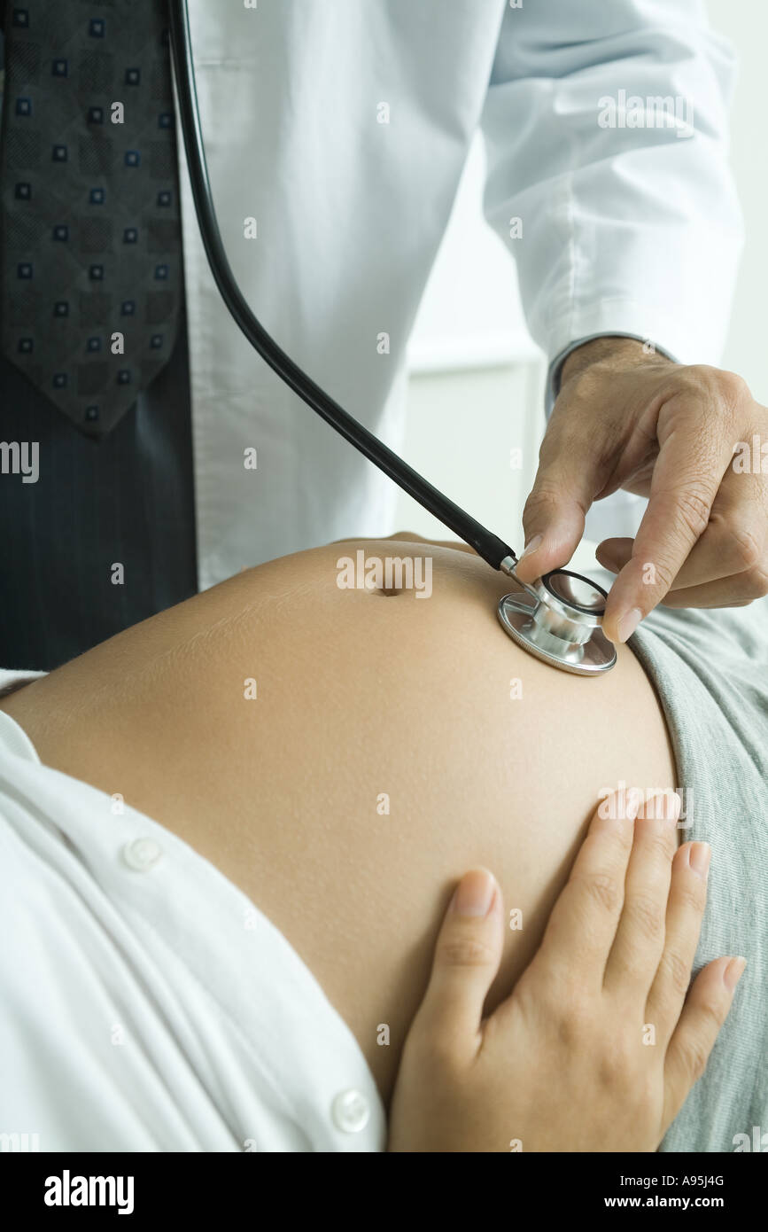 Dottore in ascolto a donne in stato di gravidanza della donna di stomaco  con uno stetoscopio Foto stock - Alamy