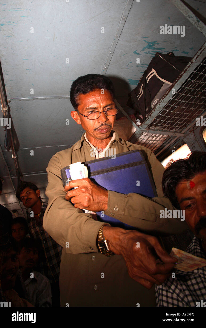 Il conduttore indiano del bus che raccoglie le tariffe fra Vadodara ad Ahmedabad, Gujarat, India Foto Stock