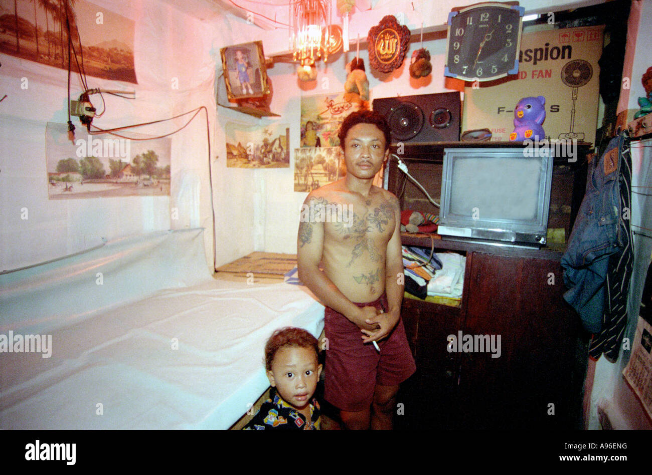 Jakarta baraccopoli l'uomo pone con il bambino in una stanza home Foto Stock