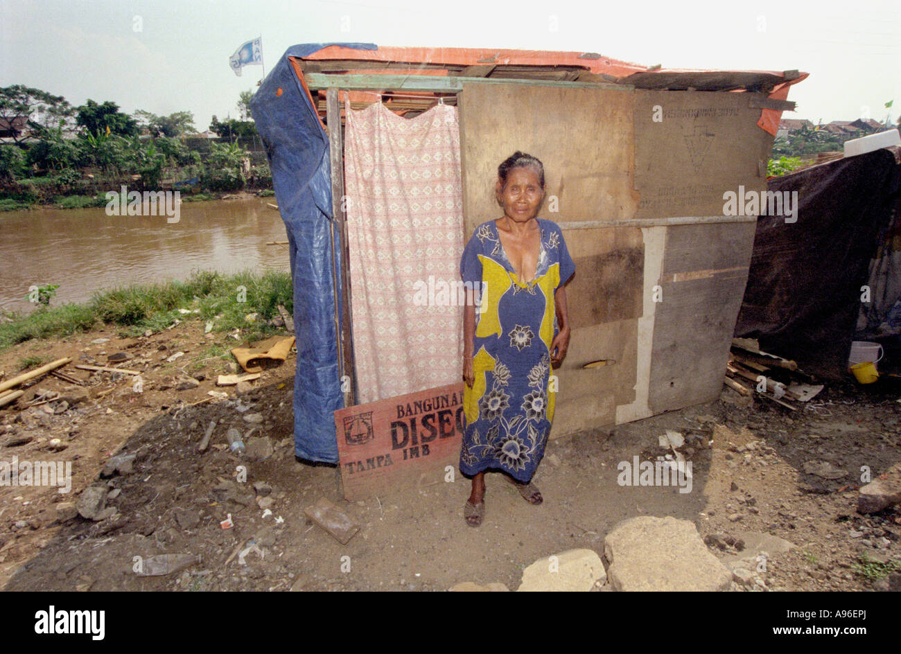 Area della baraccopoli di Giacarta 1997. La signora si posa fuori della sua casa makeeshift da un fiume inquinato che regolarmente alluvioni a causa del fatto che Giacarta sta affondando. Foto Stock