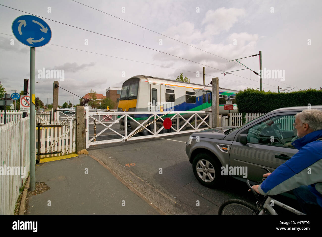 Auto in attesa di un treno in un presidiato di passaggio a livello Foto Stock