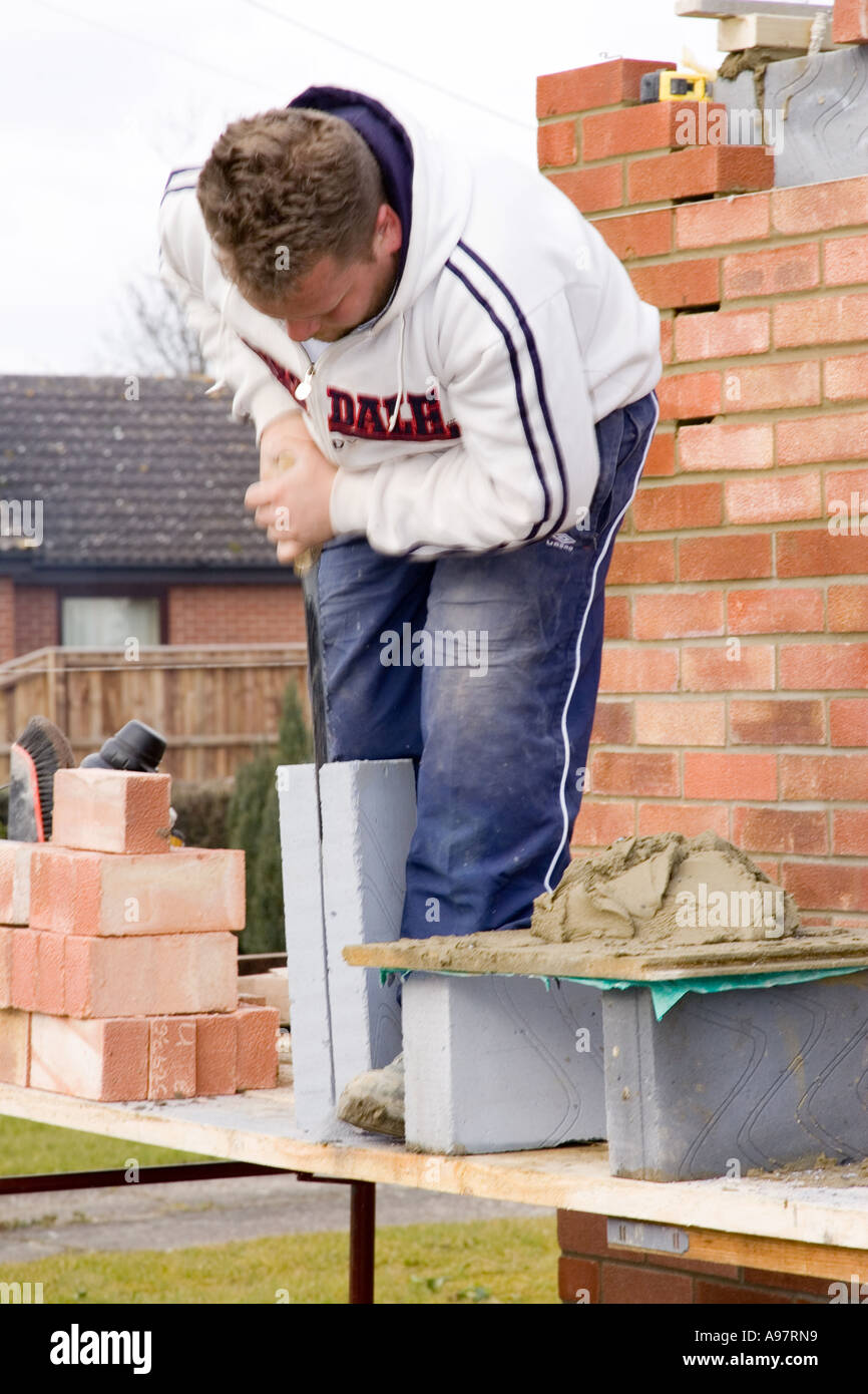 Un muratore ^il taglio di blocchi di costruzione con una sega Foto Stock