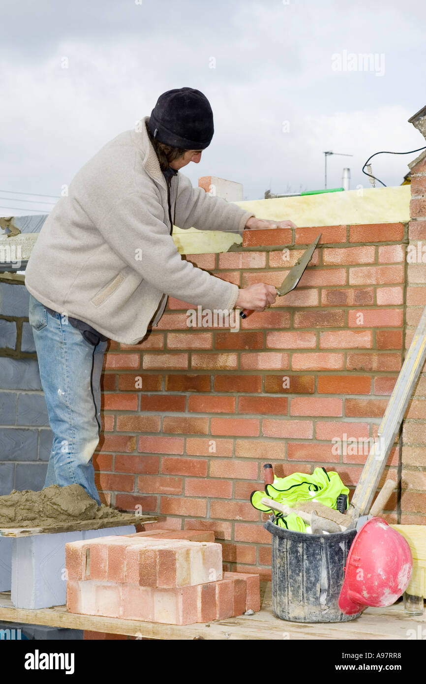 Un muratore costruire una parete per una estensione di casa Foto Stock