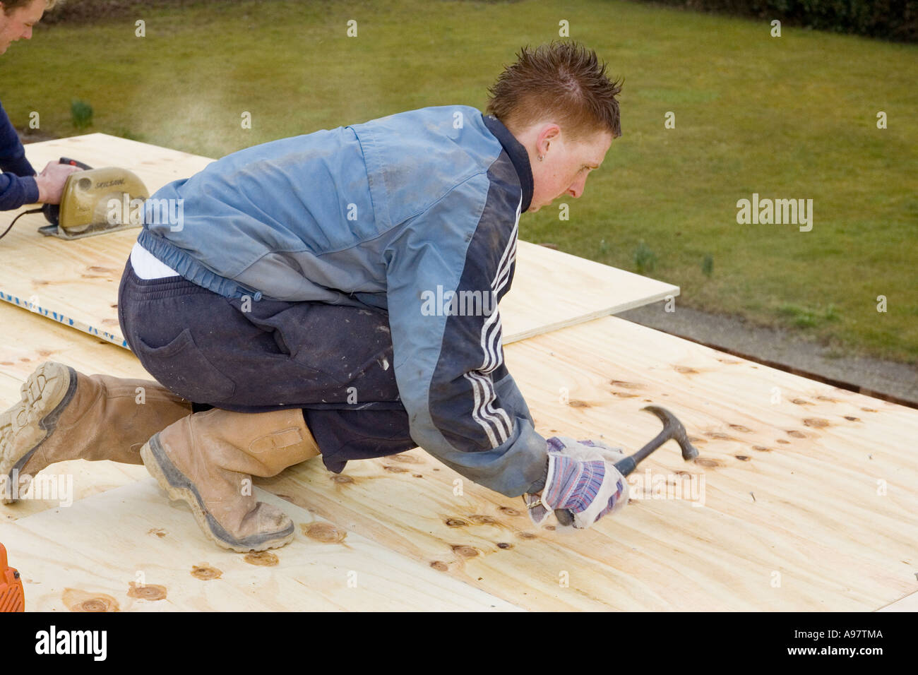 Un falegname di chiodatura, fogli di legno per formare un tetto piatto Foto Stock