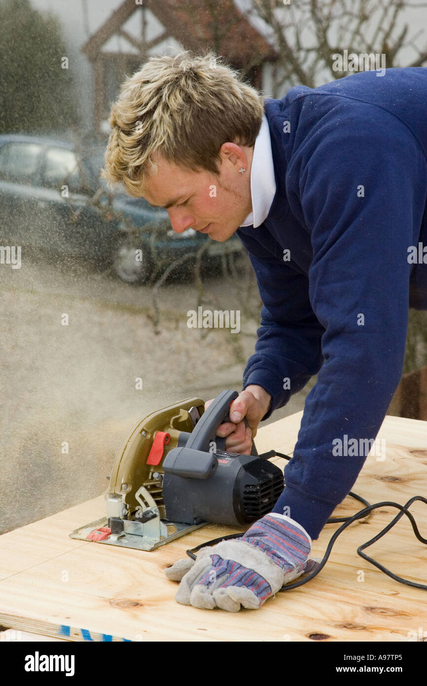 Un falegname utilizzando una sega circolare elettrica per il taglio di un foglio di legno compensato Foto Stock