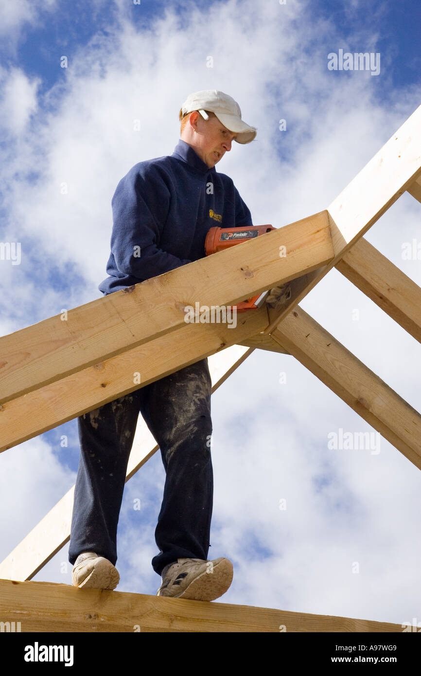 Builder contructing un nuovo padiglione per un'estensione di una casa utilizzando una pistola sparachiodi Foto Stock