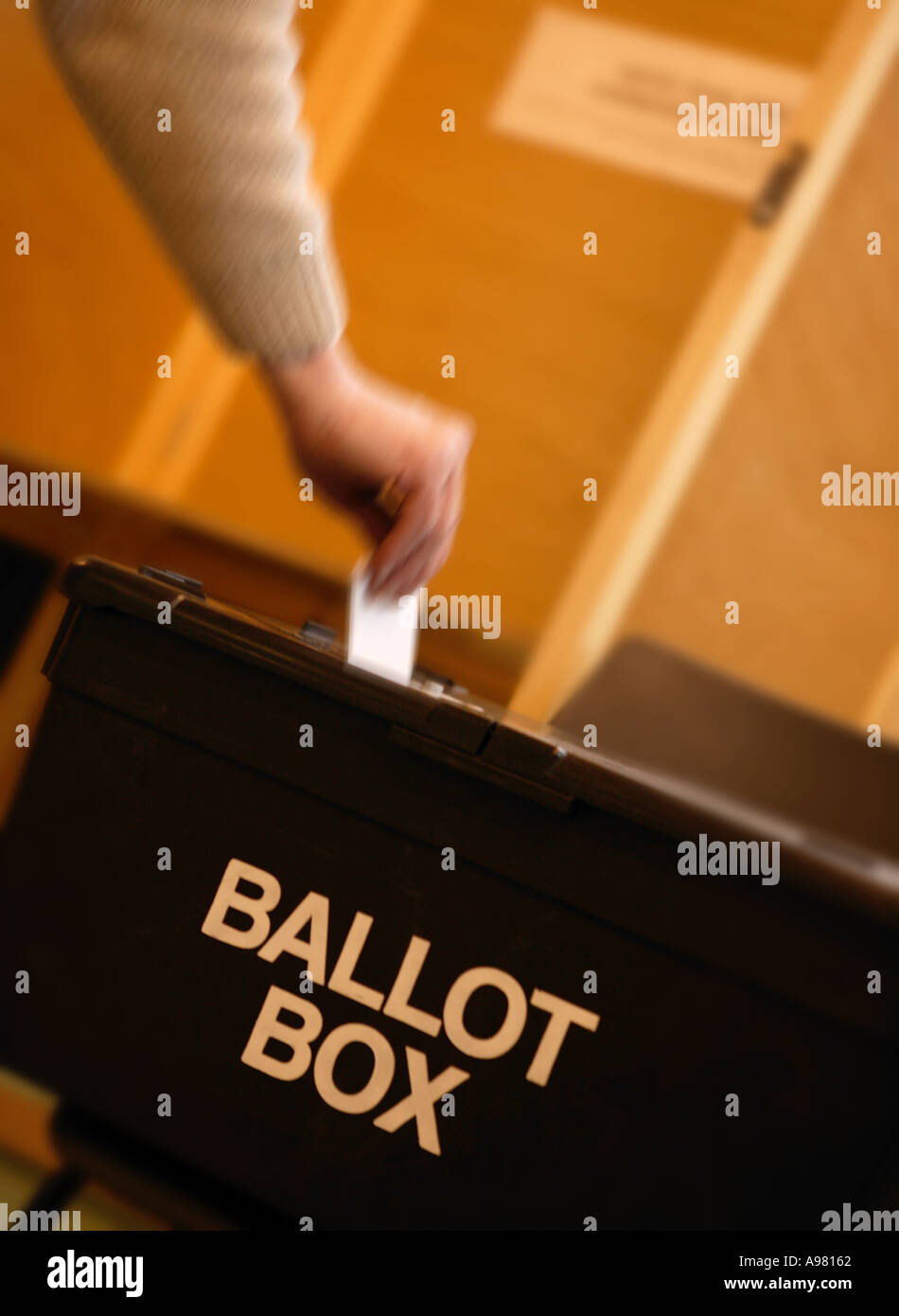 Bianco maschio man mano collocando votare nelle urne presso la stazione di polling Foto Stock