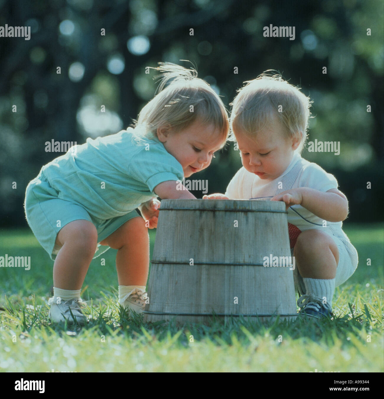Due i bambini esplorano il contenuto di un secchio di legno in posizione di parcheggio Foto Stock