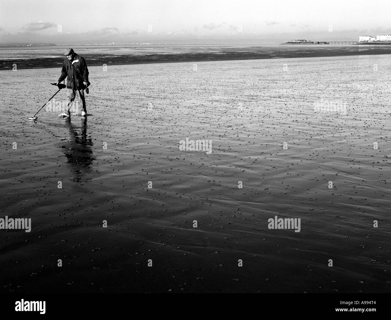Uomo su Weston-Super-Mare spiaggia con un rivelatore di metalli. (Immagine in bianco e nero) Foto Stock