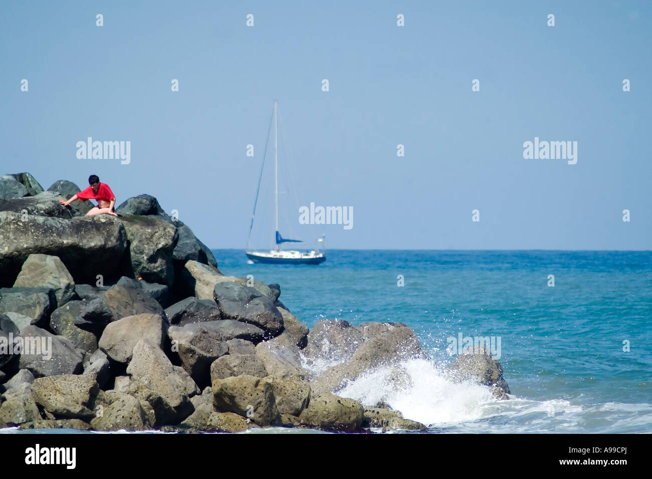 Spiaggia rocciosa a Bray testa con barca a vela Foto Stock
