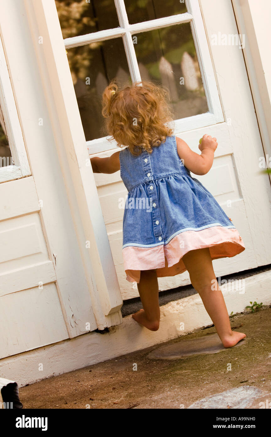 Poco ragazza camminare attraverso la porta Foto Stock
