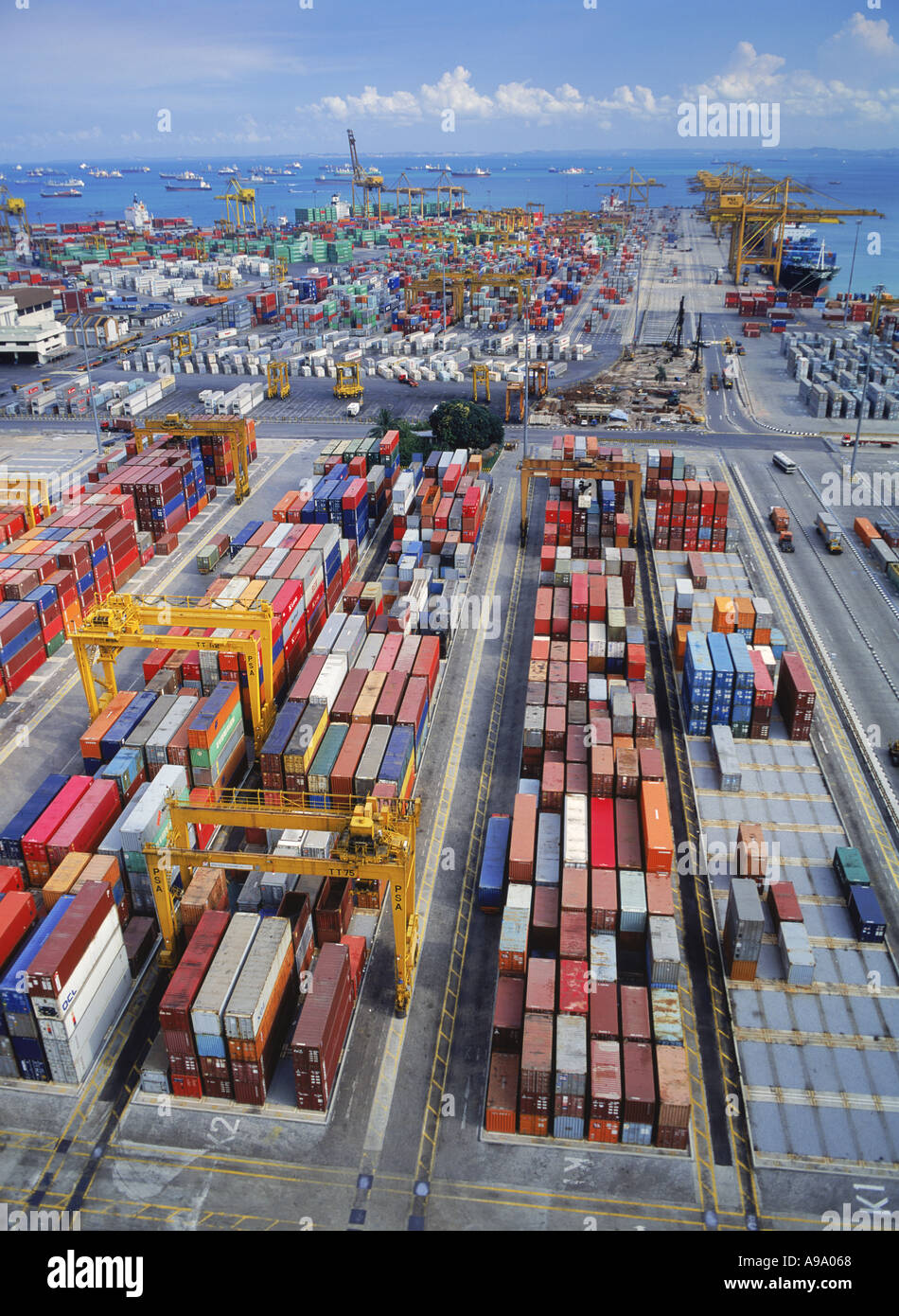 Contenitori di carico immagazzinata nel cortile con navi ancorate al largo a Singapore Foto Stock