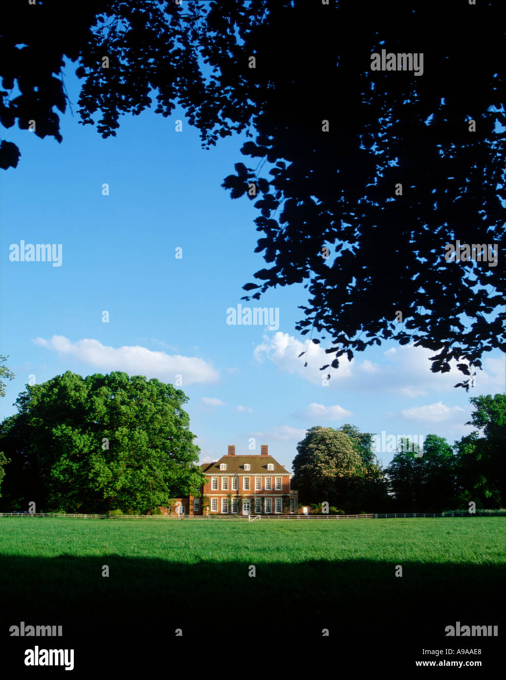 Vista distanti attraverso gli alberi attraverso il parco di eleganti inglese del XVIII secolo country house REGNO UNITO Foto Stock