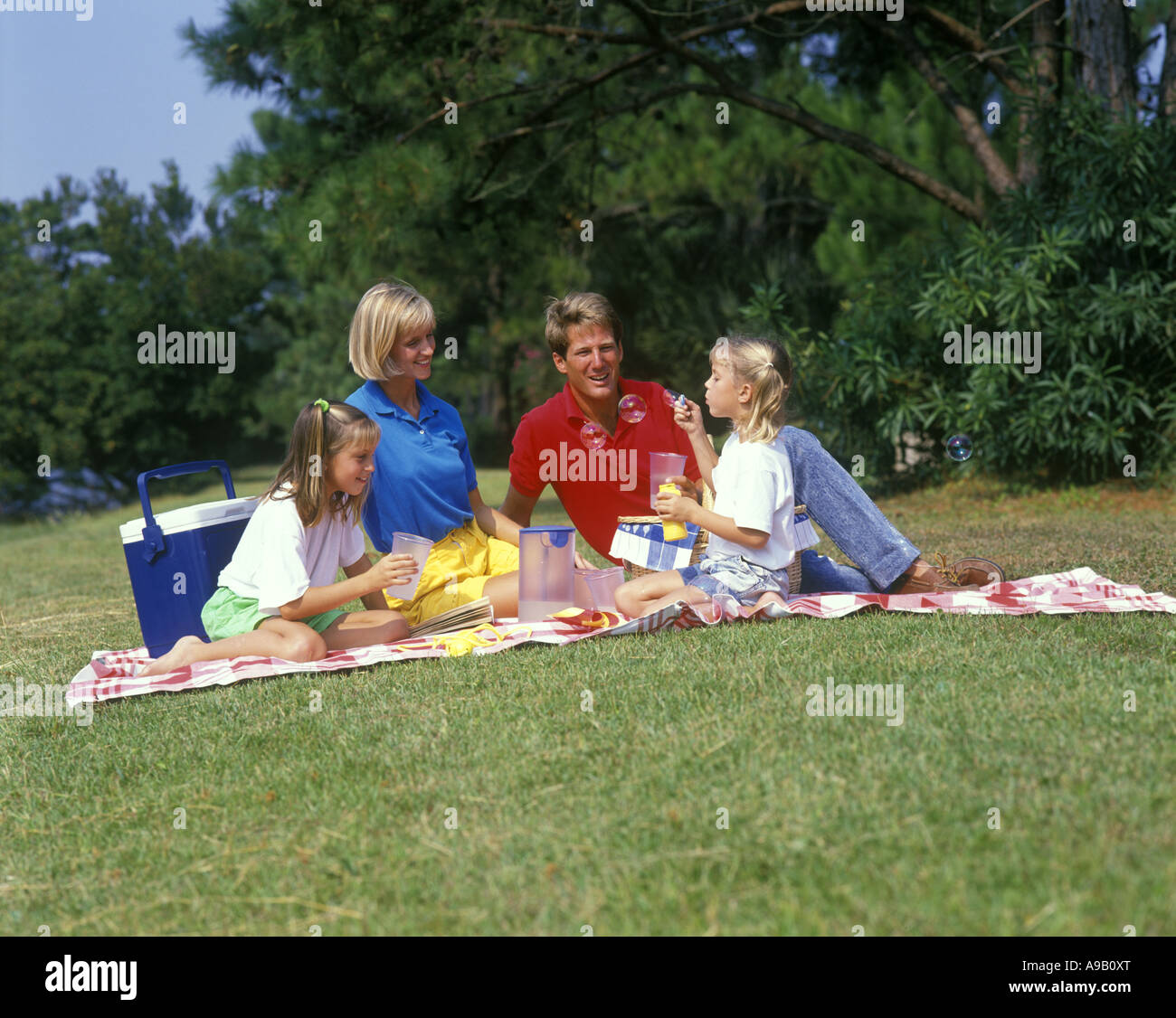 1990 STORICA FAMIGLIA NUCLEARE CAUCASICA TRADIZIONALE SEDUTA SU UNA COPERTA ALL'APERTO DURANTE UN PICNIC Foto Stock