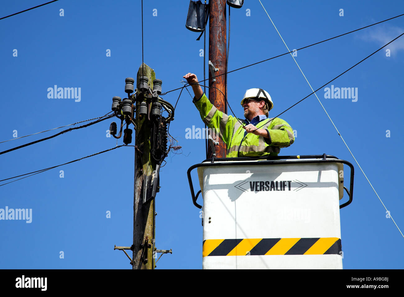 Un lavoratore di utilità in una benna telescopica la riparazione di linee telefoniche. Foto Stock
