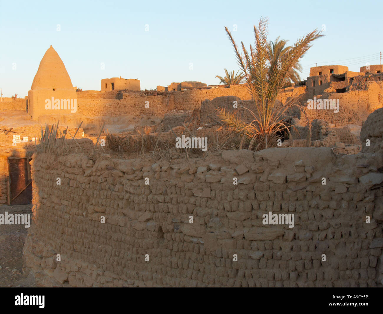 Gli antichi edifici in El Bawiti costruito in gran parte da mattoni di fango vecchie case illuminate da luce del sole serale Foto Stock