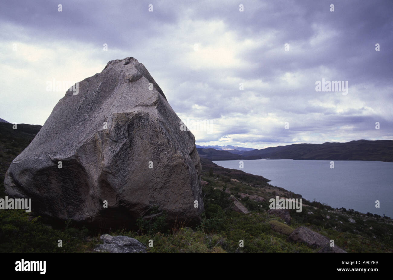 Un masso solitario sorge vegli su terra cielo e acqua Parque Nacional Torres del Paine Cile Foto Stock