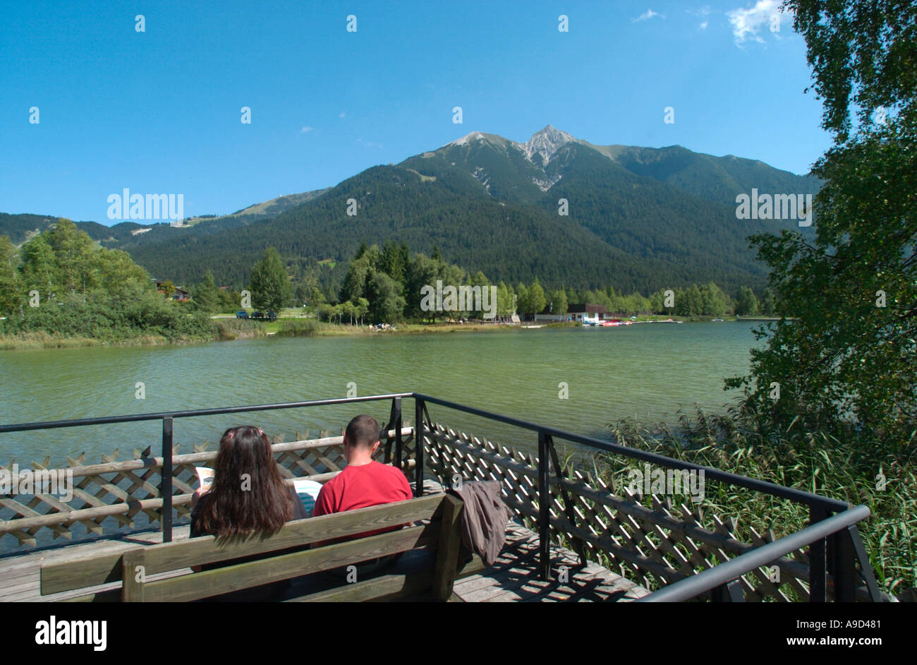 Coppia giovane seduta su una panchina in riva al lago di Seefeld, Tirolo, Austria Foto Stock