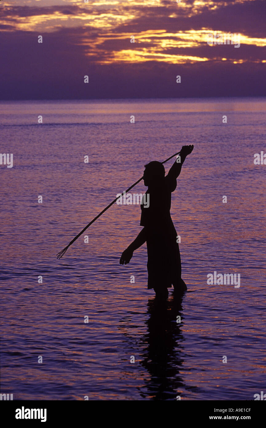 L'uomo con la lancia di pesca al tramonto nelle isole Fiji Foto Stock