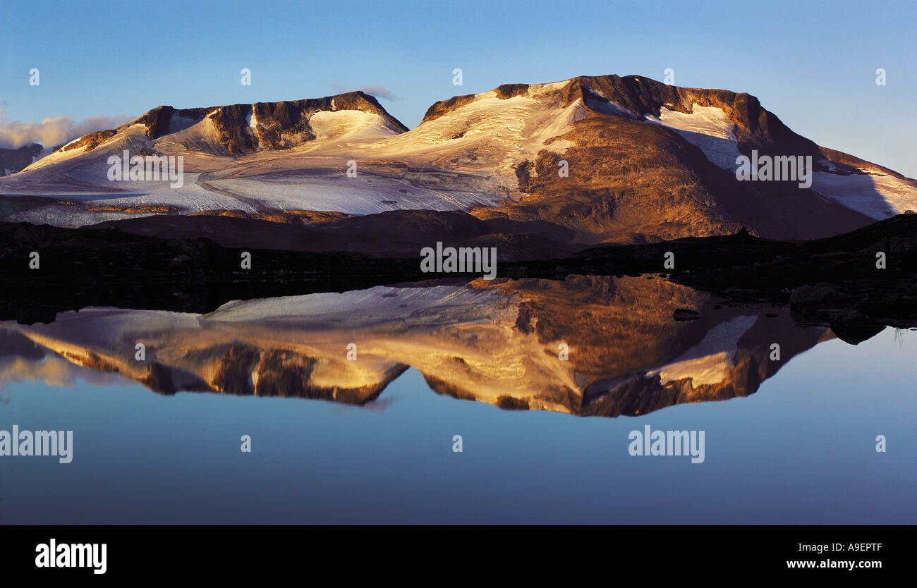 La mattina presto luce sull'Fannaraken picchi con uno specchio come riflesso in un lago glaciale Jotunheim regione Norvegia Foto Stock