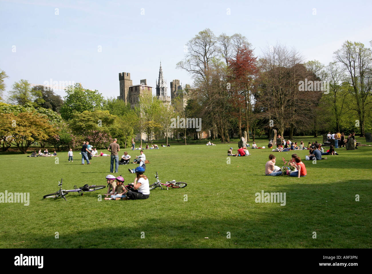 La gente seduta su erba, Bute Park e il Castello di Cardiff, Cardiff, Galles del Sud, Regno Unito Foto Stock