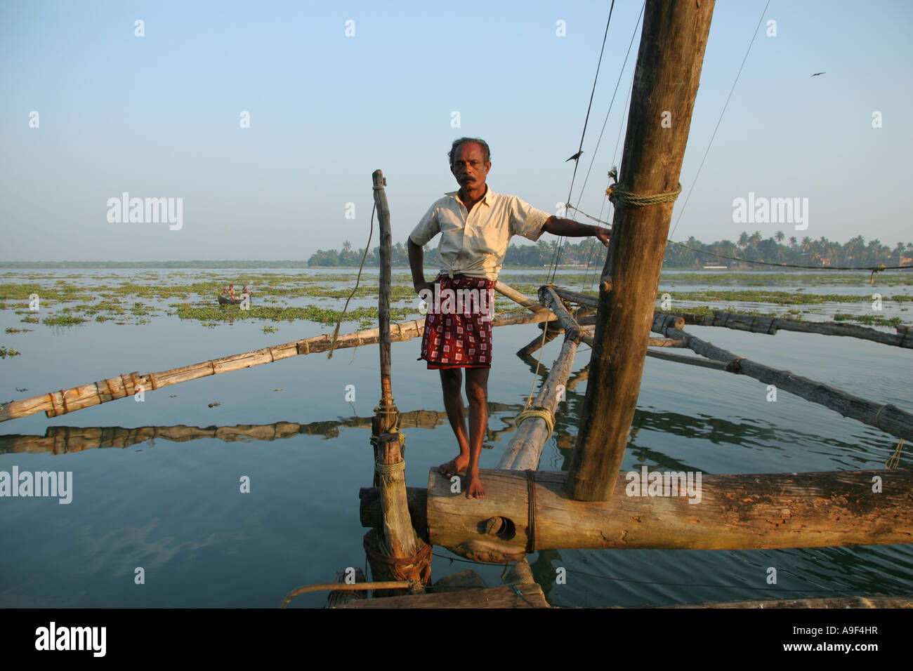 Fisherman lavorando sui cinesi reti da pesca in posa per una fotografia di Kochi (Cochin), Kerala, India del Sud Foto Stock