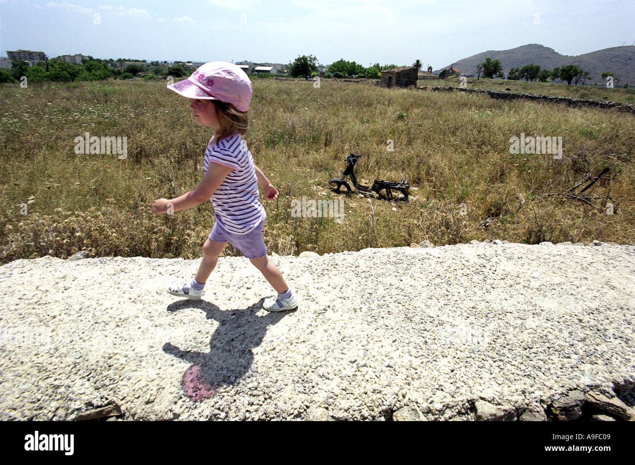 Una ragazza cammina lungo un muro con le rovine Romane sito in Alcudia Maiorca Foto Stock
